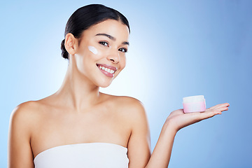 Image showing Woman, face and smile for skincare moisturizer, cosmetics or beauty against a blue studio background. Portrait of happy female smiling with product, lotion or cream for facial treatment on mockup