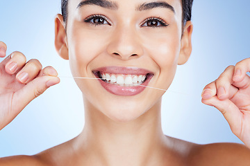 Image showing Face, flossing teeth and dental with woman, hygiene and beauty with grooming and mouth care on blue background. Hands, string and healthy gums with fresh breath, health and skin glow in portrait