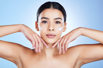 Image showing Woman, face and hands in skincare moisturizer, cosmetics or beauty against a blue studio background. Portrait of female cheeks with cosmetic product, lotion or cream for facial treatment or self love