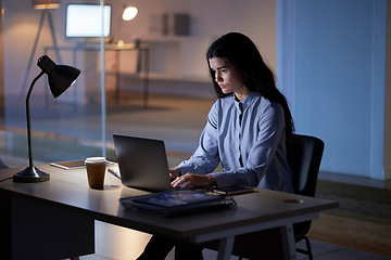 Image showing Laptop, night and business woman typing in office workplace working late on project. Computer, technology and female employee planning, internet browsing and writing research on overtime in company.