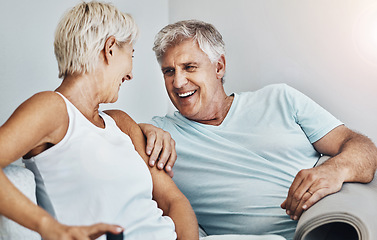 Image showing Love, laugh and retirement with a senior couple sitting in the living room of their home together. Happy, smile or relax with a mature man and woman laughing while bonding on the couch in a house