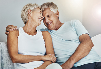 Image showing Love, laughing and retirement with a senior couple sitting in the living room of their home together. Happy, smile or relax with a mature man and woman joking while bonding on the couch in a house