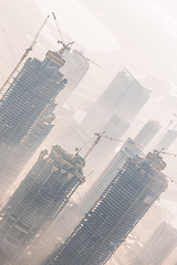 Image showing Skyscrappers construction site with cranes on top of buildings.