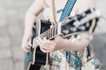 Image showing Female street musician playing guitar.