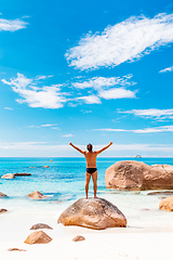 Image showing Happy man on the beautiful sandy beach rising hands to the sky on summer vacations on Seychelles. Freedom and happiness concept.