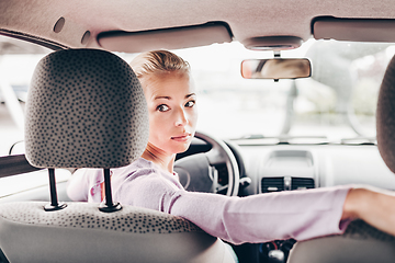 Image showing Female driver looking back while reversing in car.