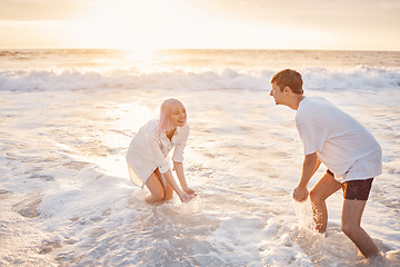 Image showing Couple at beach, splash in water with sea, travel and freedom outdoor, love and care in relationship with youth. Cafe free at sunset, nature and ocean waves with young people on holiday in Hawaii