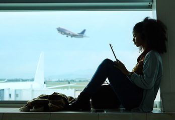 Image showing Airport, travel and black woman online with tablet by window waiting for flight, departure and transport. International plane, lobby and girl with digital tech for internet, schedule and social media