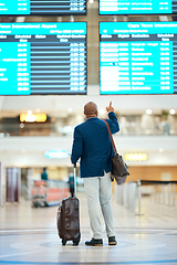 Image showing Black man, airport and pointing at flight schedule display, waiting in terminal for international business trip. Check in, travel and businessman checking foreign country destination departure time.
