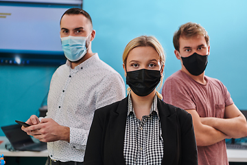 Image showing A group of colleagues stand ingin a robotics laboratory, arms crossed, wearing protective masks, symbolizing their teamwork and commitment to technological innovation and scientific research.