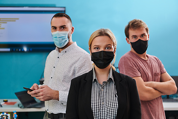 Image showing A group of colleagues stand ingin a robotics laboratory, arms crossed, wearing protective masks, symbolizing their teamwork and commitment to technological innovation and scientific research.