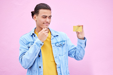 Image showing Credit card, thinking and man holding banking product with doubt of shopping, payment and ecommerce. Decision, pay choice and savings questions of a model isolated with pink background in studio