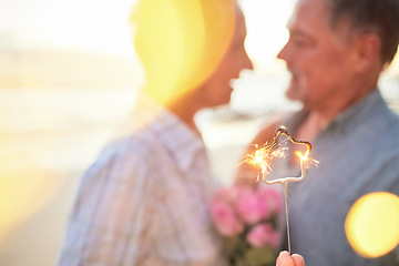 Image showing Couple, sparkler and date to celebrate love, birthday and vacation or holiday at beach in summer. Senior man and woman hug outdoor with star and bokeh for sunset dating, marriage or valentines day