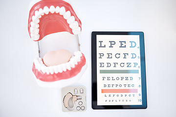 Image showing Dental, optometry and otolaryngology equipment to examine, diagnose and test isolated in a studio white background. Mouth, hearing aid and an optotype or eye chart for healthcare, medical or wellness