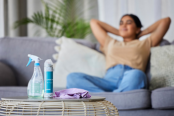 Image showing Cleaning product, woman and sofa to relax, rest or sleep for domestic work in living room with relief. Happy cleaner, lounge couch with spray, cloth and bottle on table for service, job and hygiene