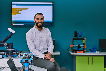 Image showing A bearded man in a modern robotics laboratory, immersed in research and surrounded by advanced technology and equipment.