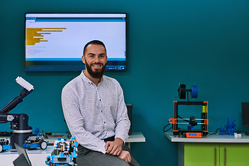 Image showing A bearded man in a modern robotics laboratory, immersed in research and surrounded by advanced technology and equipment.