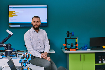 Image showing A bearded man in a modern robotics laboratory, immersed in research and surrounded by advanced technology and equipment.