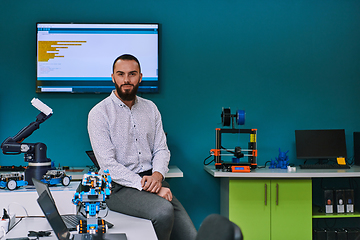 Image showing A bearded man in a modern robotics laboratory, immersed in research and surrounded by advanced technology and equipment.