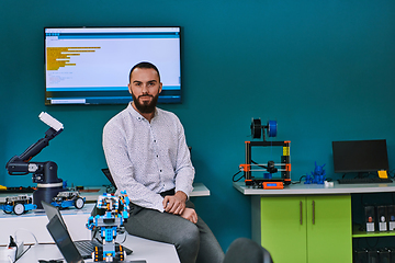 Image showing A bearded man in a modern robotics laboratory, immersed in research and surrounded by advanced technology and equipment.