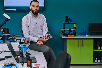 Image showing A bearded man in a modern robotics laboratory, immersed in research and surrounded by advanced technology and equipment.