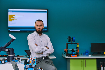 Image showing A bearded man in a modern robotics laboratory, immersed in research and surrounded by advanced technology and equipment.