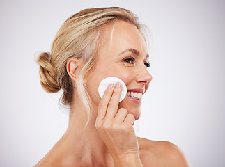 Image showing Face, cotton and skincare with a mature woman in studio on a gray background cleaning her skin for exfoliation. Relax, luxury and product with a female using a pad to cleanse her pores for beauty