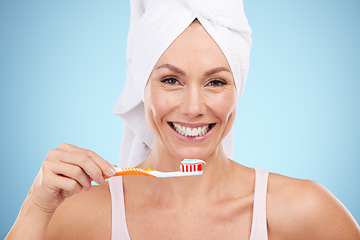 Image showing Mature woman, portrait and brushing teeth isolated on blue background dental, mouth or orthodontics healthcare. Beauty model or face of happy person with toothbrush product and toothpaste in studio