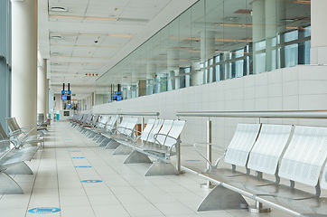 Image showing Empty airport, terminal lounge and chair furniture in waiting room of departure, global travel or transportation. Airplane lobby, seat and space of commercial flight, building interior or backgrounds