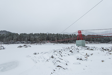 Image showing Suspension hanging bridge above winter frozen river