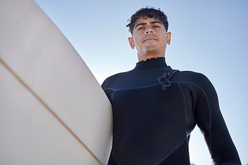 Image showing Surfing, beach and serious surfer with blue sky outdoor for water sports, training and exercise. Surfboard, morning workout and sea with summer sun and man ready for sport and freedom at the ocean