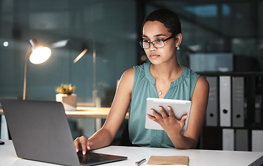 Image showing Serious, accountant or black woman at night on laptop and tablet for financial strategy, tax or audit review for company growth. Finance or advisor for planning stock market, investment research