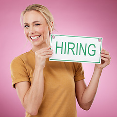 Image showing Hiring, sign and portrait of a woman for recruitment, job search and advertising opportunity. Smile of a happy business person with a poster for recruiting and human resources on a pink background