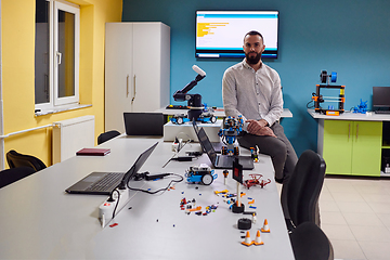 Image showing A bearded man in a modern robotics laboratory, immersed in research and surrounded by advanced technology and equipment.