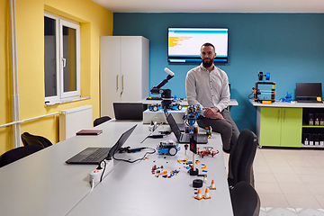 Image showing A bearded man in a modern robotics laboratory, immersed in research and surrounded by advanced technology and equipment.