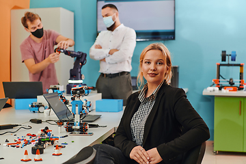 Image showing A woman sitting in a laboratory while her colleagues test a new robotic invention in the background