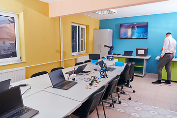 Image showing A bearded man in a modern robotics laboratory, immersed in research and surrounded by advanced technology and equipment.