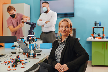 Image showing A woman sitting in a laboratory while her colleagues test a new robotic invention in the background