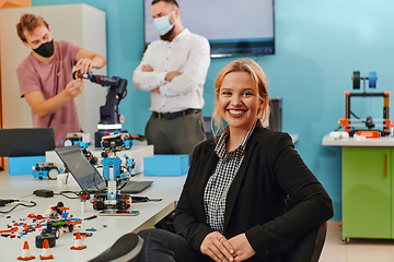 Image showing A woman sitting in a laboratory while her colleagues test a new robotic invention in the background