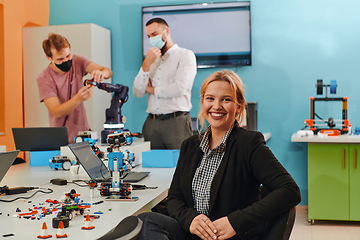 Image showing A woman sitting in a laboratory while her colleagues test a new robotic invention in the background