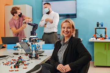 Image showing A woman sitting in a laboratory while her colleagues test a new robotic invention in the background