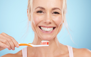 Image showing Portrait, mature woman and brushing teeth isolated on blue background in dental, mouth or orthodontics healthcare. Beauty model or happy person face for toothbrush product and toothpaste in studio