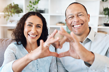 Image showing Hand, heart and portrait of mature couple with love on sofa for bond, romance and happy in living room. Hands, emoji and face of older man with woman, happy or smile while enjoying retirement at home