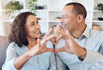 Image showing Hand, heart and mature couple with love on a sofa for bonding, romance and happy in a living room. Hands, emoji and romantic older man with woman, happy and smile while enjoying retirement lifestyle