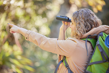 Image showing Woman hiking, forest and binoculars with point, vision and birdwatching on outdoor adventure in summer. Happy hiker girl, free and search in woods, forrest and focus on walk with backpack on holiday