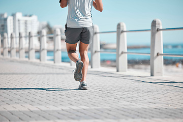 Image showing Fitness, legs and man running by ocean in action for wellness, run performance and athlete endurance. Movement, motivation and male runner by sea for exercise, marathon training and cardio workout