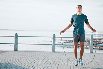 Image showing Skipping rope, mockup and man training by the beach for his outdoor morning exercise, workout and fitness routine. Athlete, cardio and male jump by the ocean or sea for wellness lifestyle