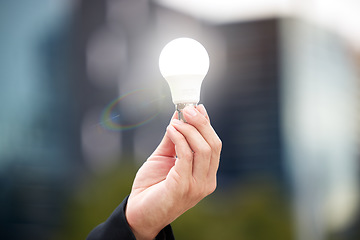 Image showing Hands, light bulb and idea in the city for solution, eco friendly or renewable energy on blurred background. Hand of person holding lamp for creativity, ideas or power saving element on mockup