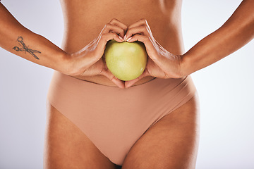 Image showing Woman hands, studio and apple in heart sign on diet, wellness or lose weight by gray background. Model, fruit and stomach for healthcare, digestion or nutrition with lifestyle choice for clean eating