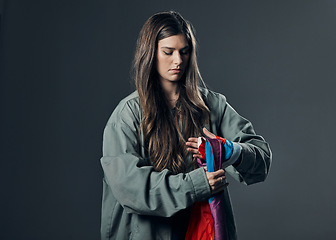 Image showing Protest, LGBTQ and woman with flag in studio wrapping it on hand for human rights and equality. Empowerment, sexuality and female political activist with bisexual material isolated by gray background